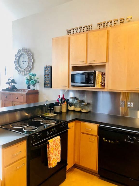 A kitchen with wooden cabinets and black appliances at Lofts at Lafayette Square Apartments, Saint Louis, MO, 63104