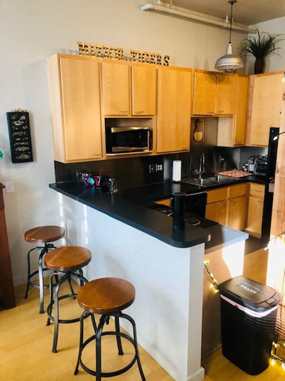 A kitchen with wooden cabinets and a black countertop at Lofts at Lafayette Square Apartments, Missouri, 63104