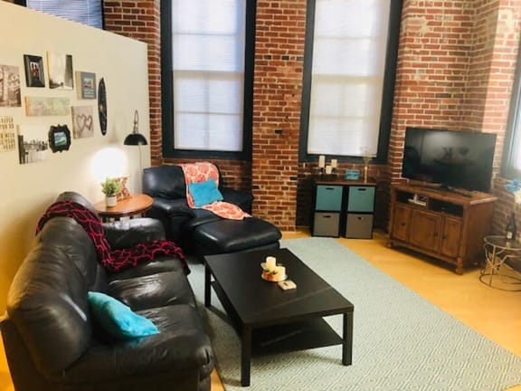 A black leather couch with a red and black throw blanket on it at Lofts at Lafayette Square Apartments, Missouri