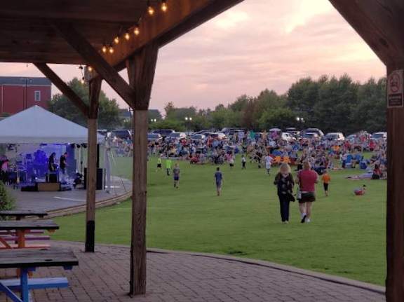 A large gathering of people are sitting on the grass at French District Villas Apartments, St. Charles, MO