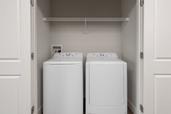 Two white front load washing machines in a laundry room.