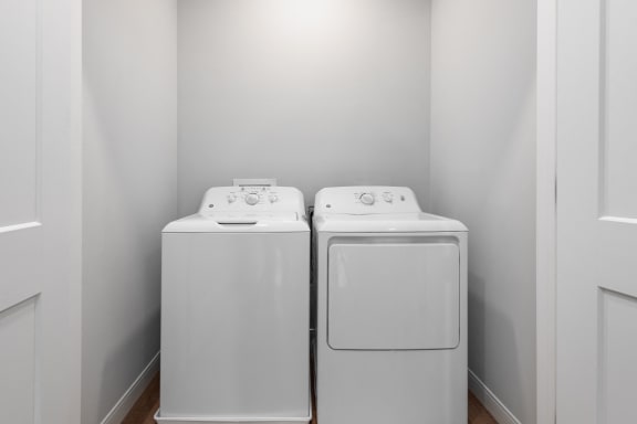 a washer and dryer in a laundry room with white walls at The Flats &amp; Terraces at Wildhorse Village, Chesterfield