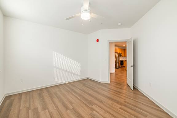 A room with a ceiling fan and wooden flooring.