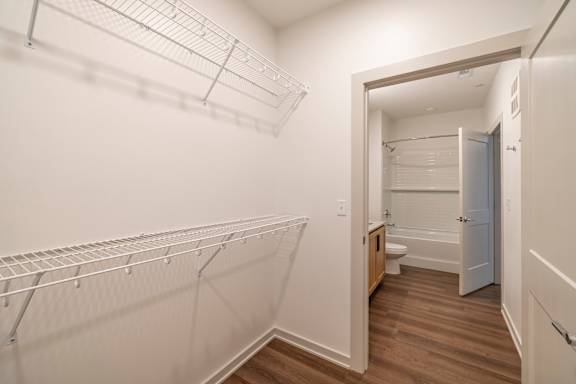 A walk-in closet with a doorway leading to a bathroom.