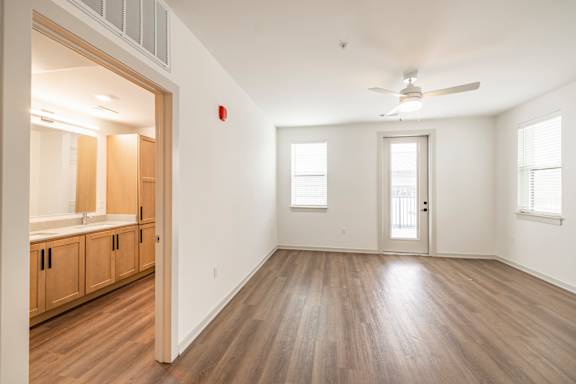 A room with a ceiling fan and a door leading to another room.