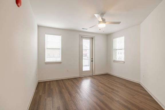 A room with a ceiling fan and wooden flooring.