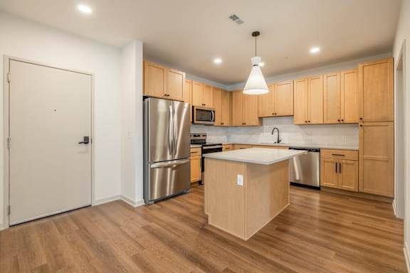 A kitchen with wooden cabinets and a white island.