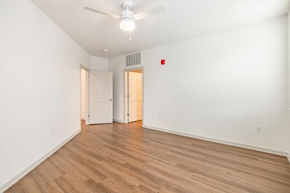 A room with a ceiling fan and wooden flooring.