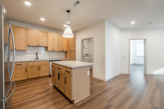 A kitchen with wooden cabinets and a white island.