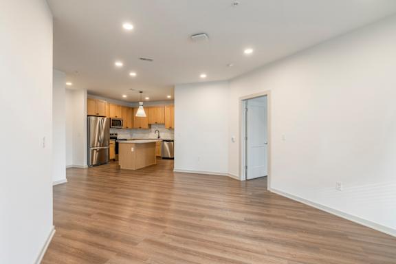 A large empty room with wooden flooring and white walls.