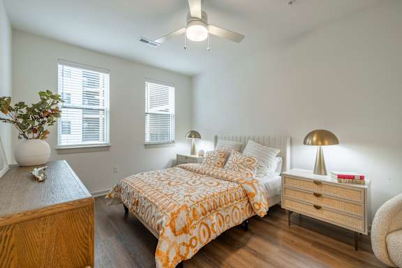 A bedroom with a bed, nightstand, and a plant on a wooden table.