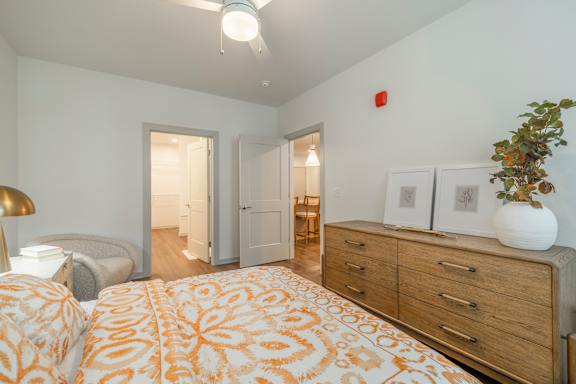 A bedroom with a bed, dresser, and two doors.