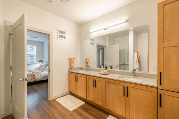 A bathroom with a sink, mirror, and wooden cabinets.