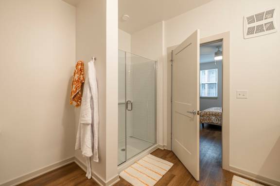 A white towel is hanging on a white wall next to a glass door.