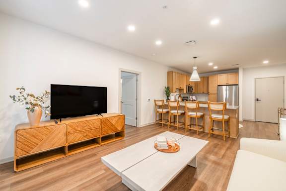 A modern living room with a television, a coffee table, and a dining area.