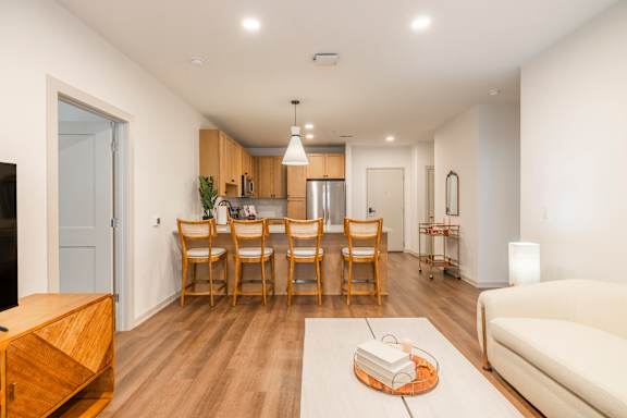 A modern living room with a dining area and a kitchen in the background.