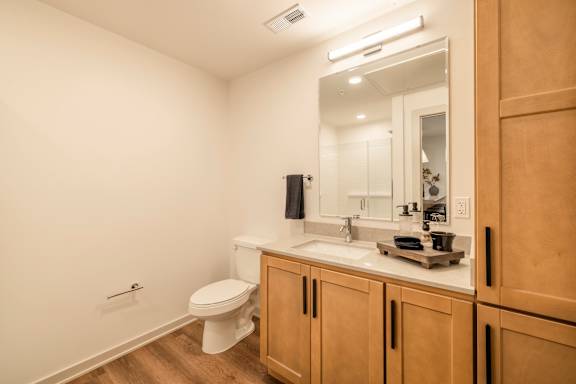 A bathroom with a toilet, sink, and mirror.