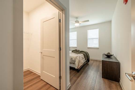 A bedroom with a bed, nightstand, and a window with blinds.