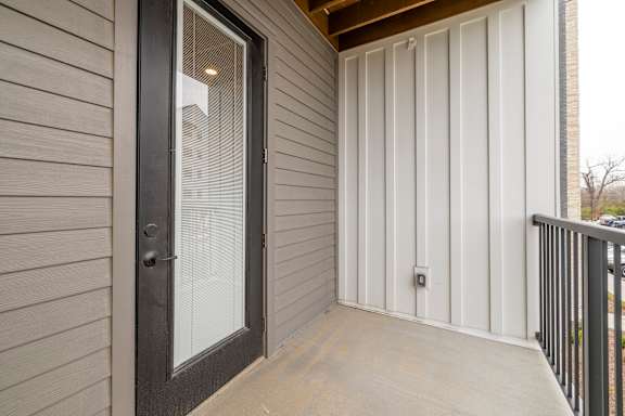 A balcony with a glass door and a black railing.