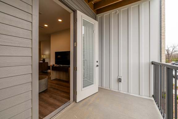 A white door is open to a room with a wooden floor.