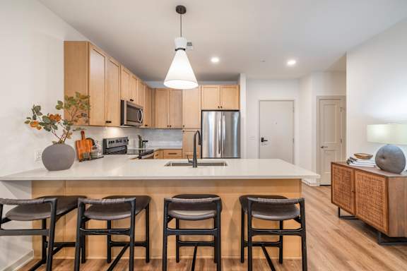 A kitchen with a white countertop and bar stools.
