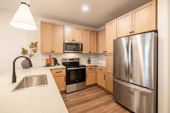 A kitchen with a stainless steel refrigerator and wooden cabinets.