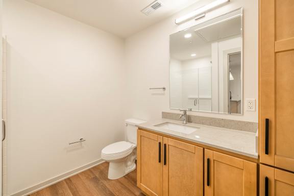 A bathroom with a toilet, sink, and mirror.