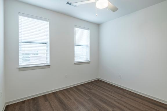A room with two windows and wooden flooring.