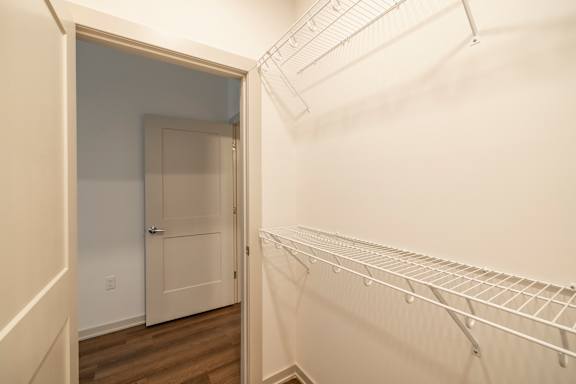 A white closet with a door and shelves.