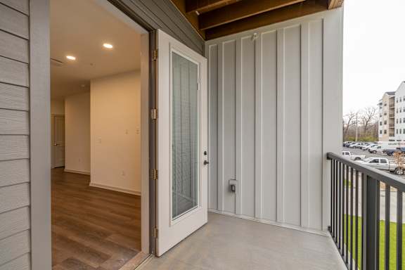 A white door is open to a room with a wooden floor.