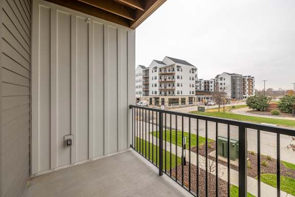 A balcony with a black railing overlooks apartment buildings.