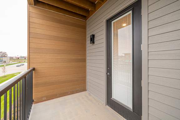 A balcony with a glass door and a black railing.