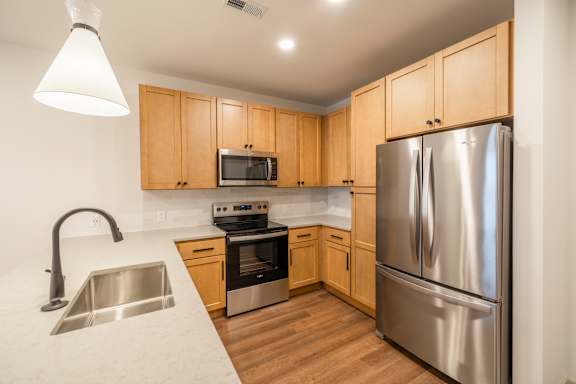 A kitchen with a stainless steel refrigerator, microwave, oven, and sink.