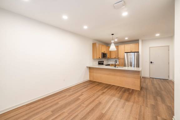 A kitchen with wooden floors and a white wall.