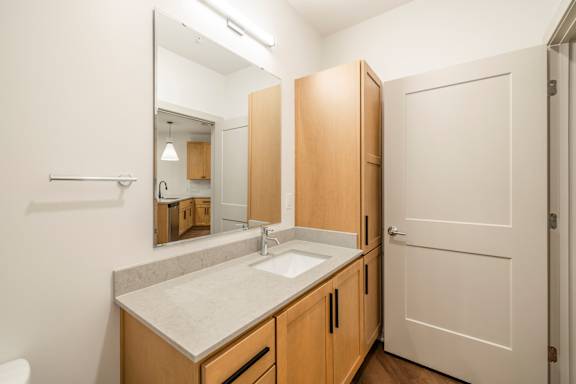 A bathroom with a sink, mirror, and wooden cabinets.