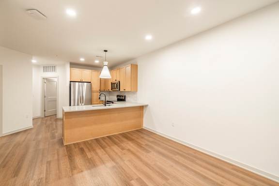 A kitchen with wooden floors and a white wall.