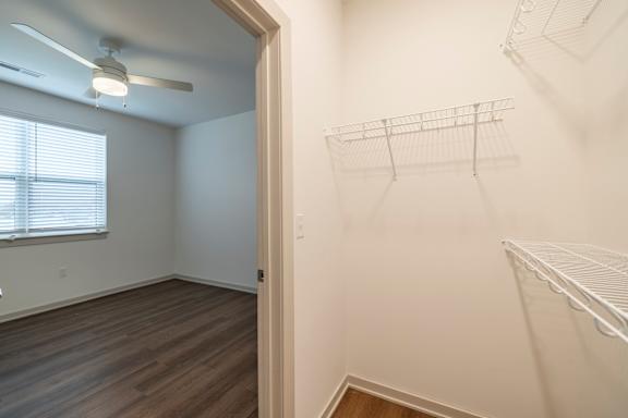 A room with a fan and a window with blinds.