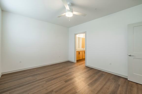 A room with wooden flooring and a ceiling fan.