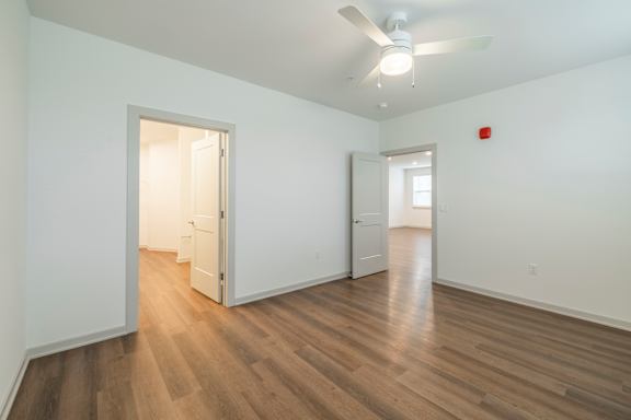 A room with a ceiling fan and wooden flooring.