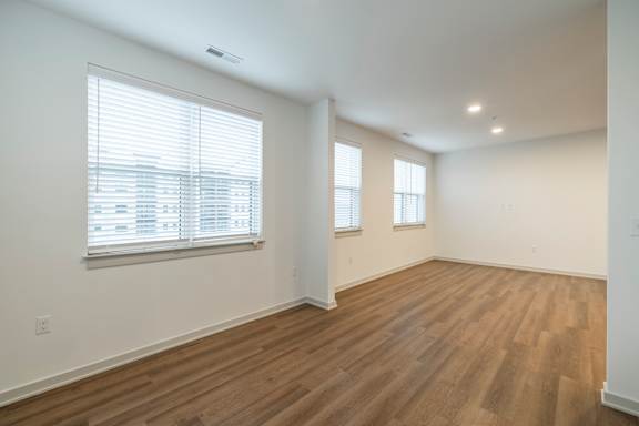 A room with wooden floors and two windows.