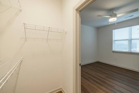 Empty room with a window and a fan on the ceiling.