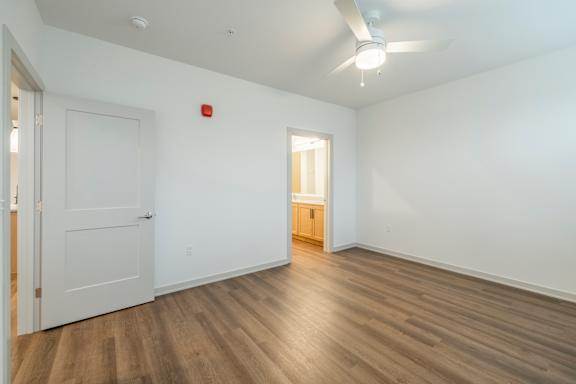 A room with a white door and a wooden floor.