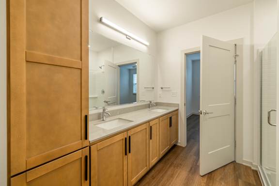 A bathroom with a sink, mirror, and wooden cabinets.
