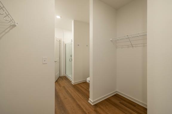 A hallway with a white wall and a wooden floor.