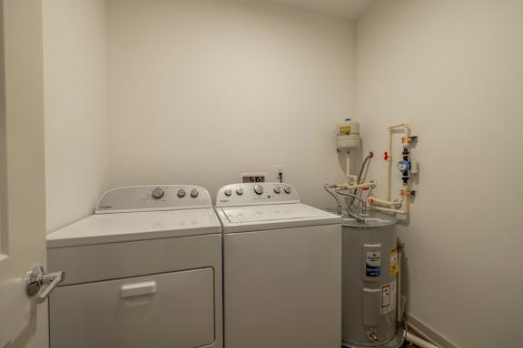 A small room with two washing machines and a water heater.
