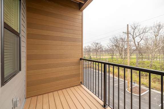 A balcony with a black railing and wooden floor.