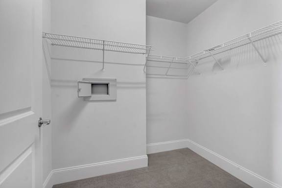 A white room with a door and a small white box on the wall.