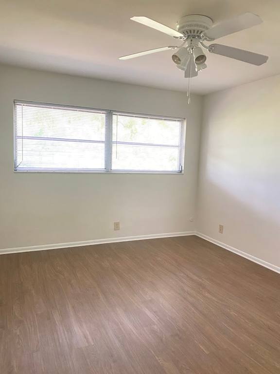A room with a ceiling fan and a window with blinds.