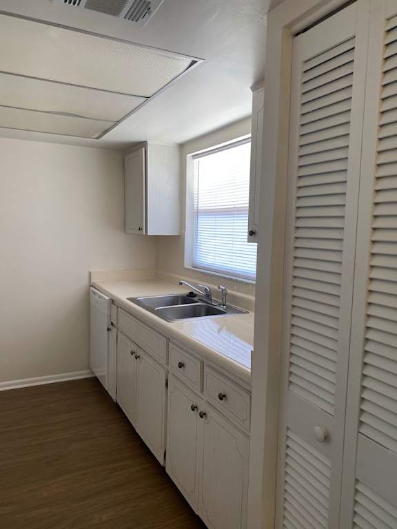 A white kitchen with wooden floors and a window.