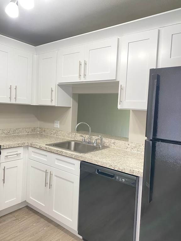 A kitchen with white cabinets and a black refrigerator.